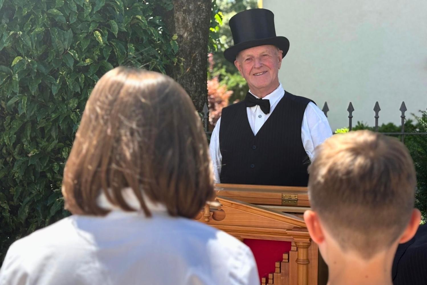 Zwei Kinder stehen vor einem Orgelspieler.